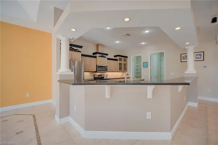 Kitchen featuring a kitchen bar, ornate columns, stainless steel appliances, and recessed lighting