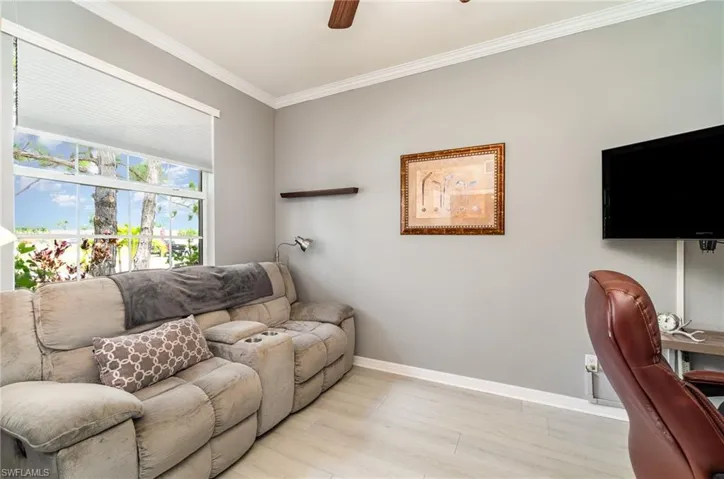Living room featuring ceiling fan, ornamental molding, and light hardwood / wood-style flooring