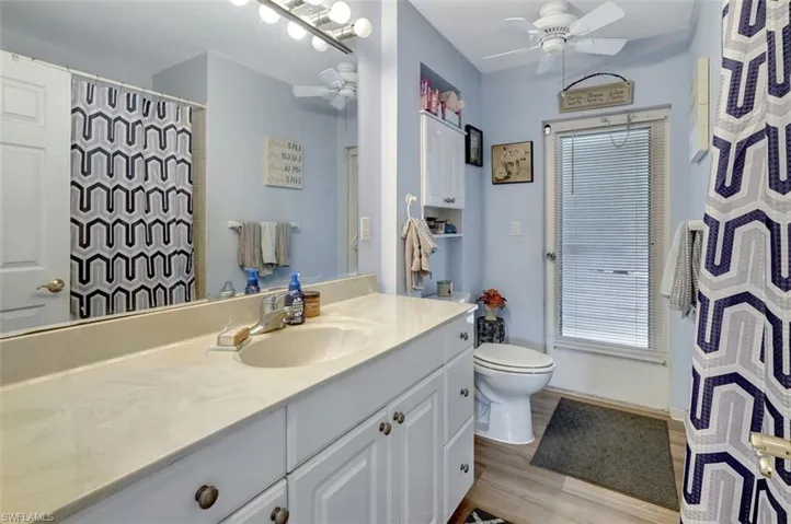 Bathroom featuring toilet, ceiling fan, vanity, and wood-type flooring