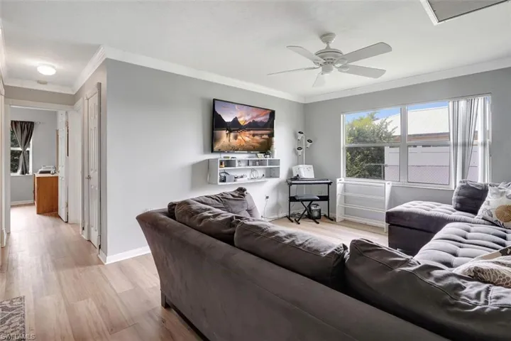 Living room featuring ceiling fan, crown molding, and light hardwood / wood-style flooring