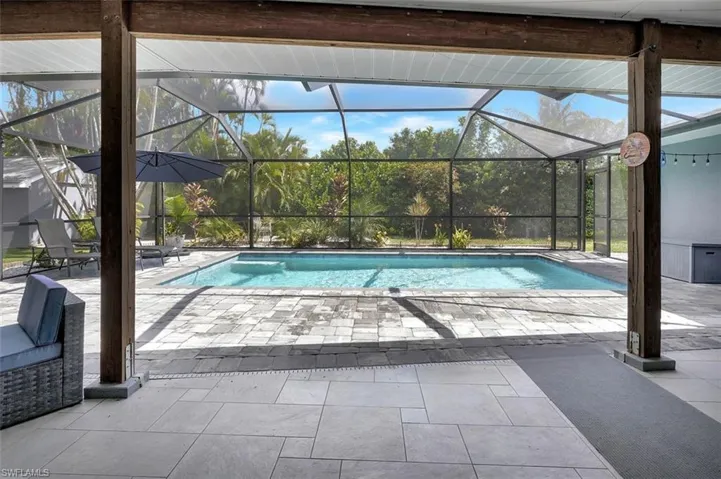 View of swimming pool featuring glass enclosure and a patio