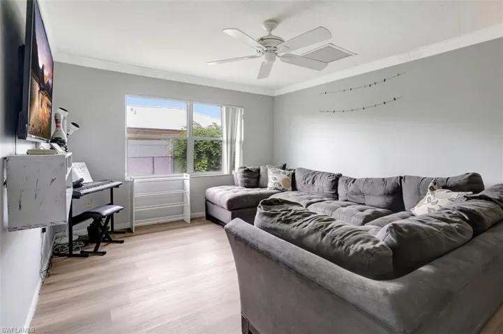 Living room featuring ceiling fan, crown molding, and light wood-type flooring