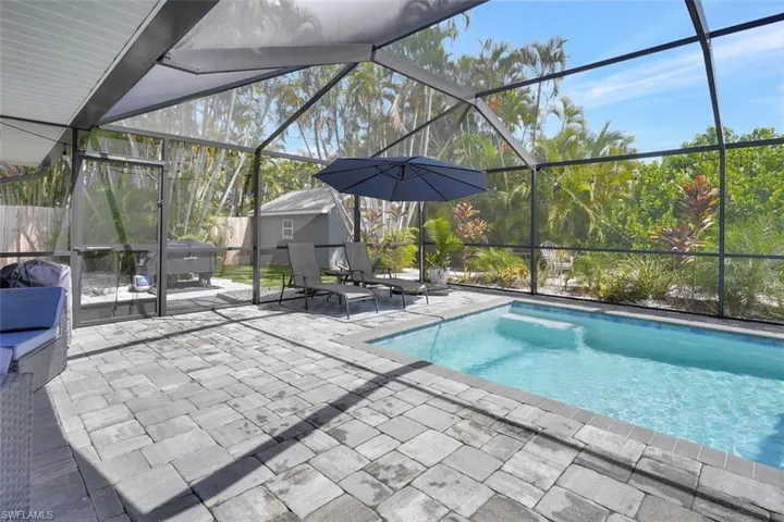 View of swimming pool featuring a patio area, a grill, a lanai, and a storage unit