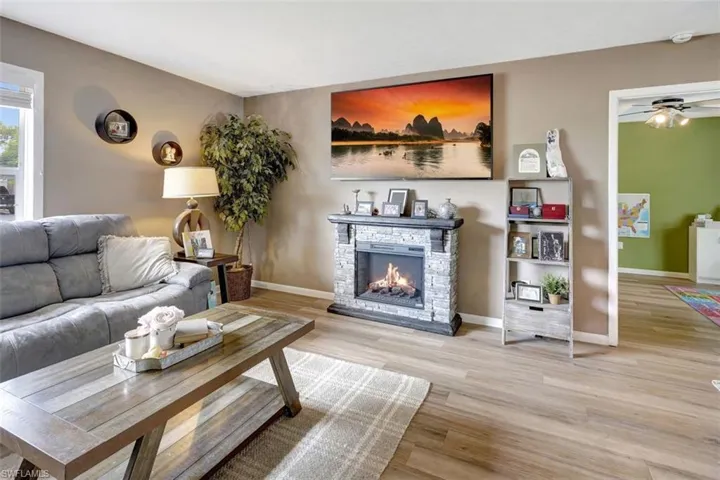 Living room featuring ceiling fan, a fireplace, and light hardwood / wood-style flooring