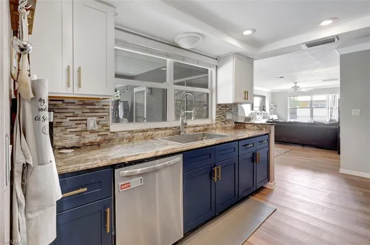 Kitchen with light hardwood / wood-style floors, white cabinets, blue cabinetry, and dishwasher