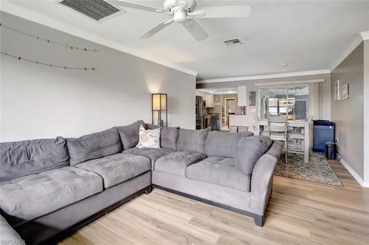 Living room with ceiling fan, crown molding, and light hardwood / wood-style floors