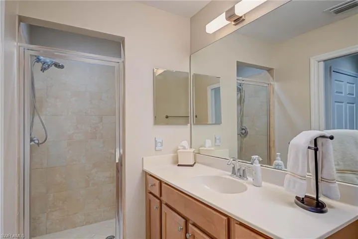 Bathroom with vanity, a stall shower, and visible vents
