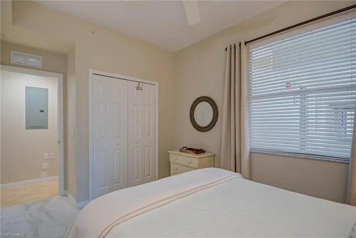 Bedroom with a closet, light tile patterned flooring, baseboards, electric panel, and a ceiling fan