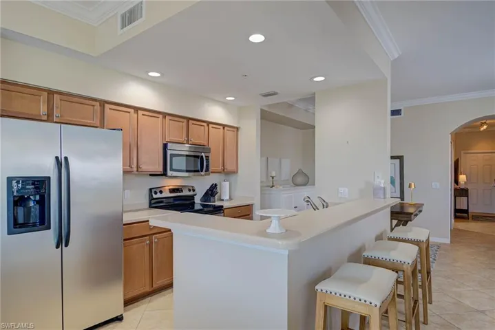 Kitchen with visible vents, light tile patterned flooring, a breakfast bar, arched walkways, and stainless steel appliances