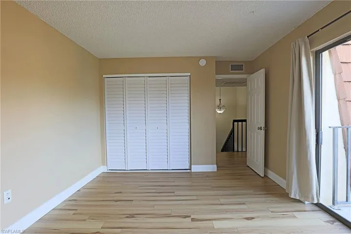 Unfurnished bedroom with light wood-type flooring, a textured ceiling, and a closet