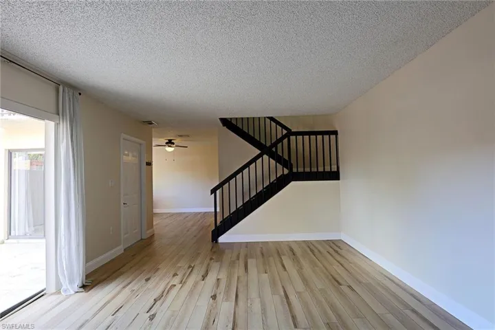 Stairs featuring wood finished floors, a textured ceiling, and a ceiling fan
