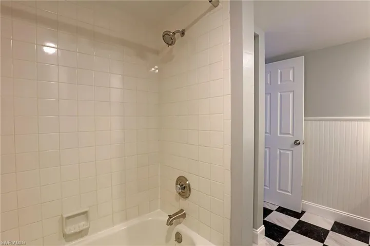 Bathroom with tub / shower combination, wainscoting, and tile patterned floors