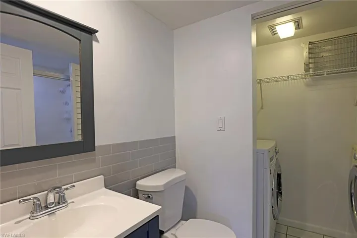 Bathroom with vanity, washing machine and clothes dryer, and tile walls