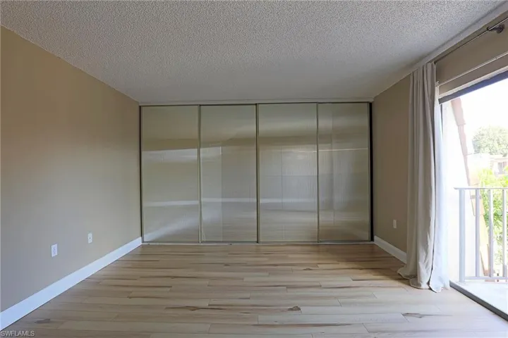 Unfurnished bedroom featuring a textured ceiling, light wood finished floors, and a closet