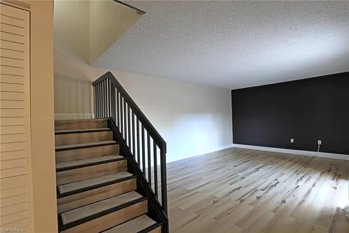 Stairway with wood finished floors and a textured ceiling