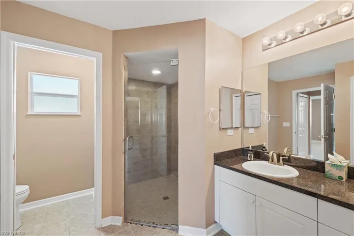 Bathroom with vanity, toilet, walk in shower, and tile patterned flooring