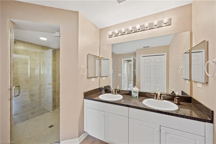 Bathroom featuring a shower with door, tile patterned floors, and vanity