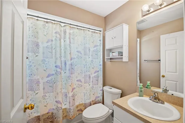 Bathroom featuring vanity, curtained shower/tub, and toilet