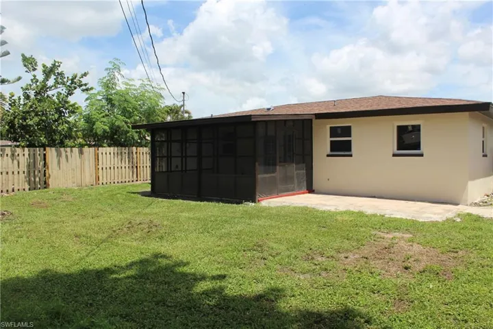 Rear view of house with a sunroom, stucco siding, a patio area, and a shingled roof