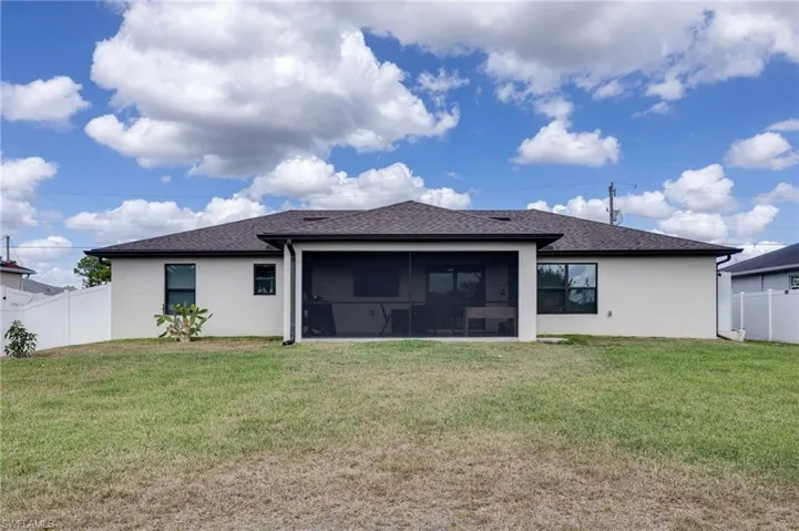 Rear view of property featuring roof with shingles, stucco siding, and a sunroom