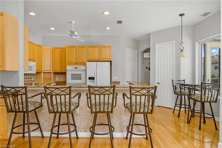 Kitchen featuring stone counters, pendant lighting, light wood-type flooring, and ceiling fan