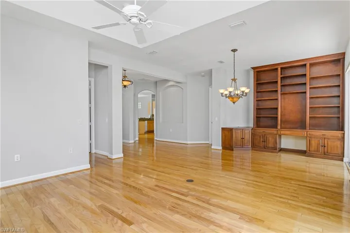 Open living room/dining room with custom built-in shelving and beautiful hard wood flooring.