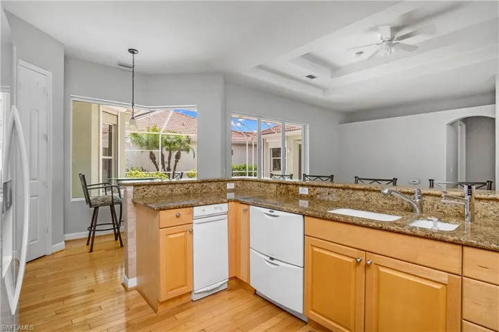 Kitchen with stone counters, light hardwood / wood-style flooring, white appliances, tasteful backsplash, and ceiling fan