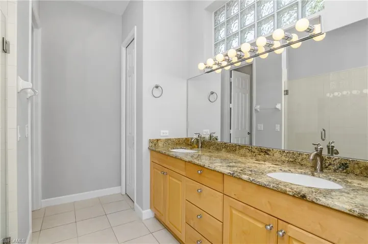 Bathroom featuring ceiling fan, double sink vanity, a shower with door, and tile patterned flooring