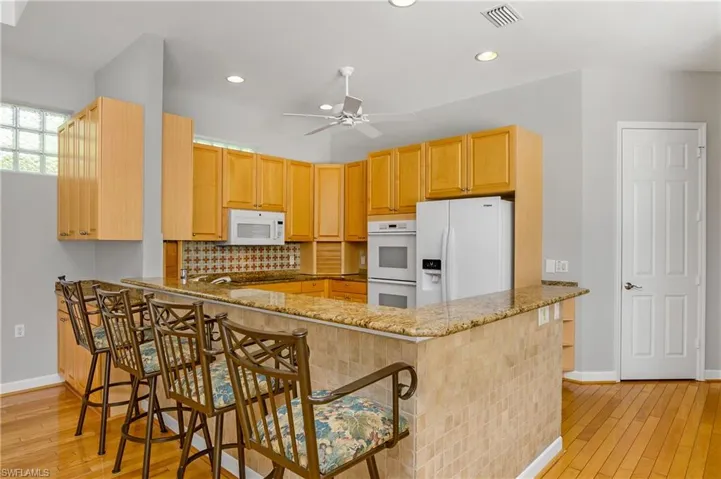 Kitchen featuring kitchen peninsula, light hardwood / wood-style flooring, and white appliances