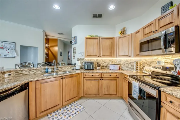 Kitchen featuring stainless steel appliances, tasteful backsplash, light tile patterned floors, light stone counters, and recessed lighting