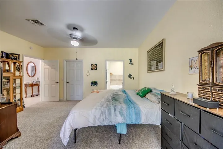 Carpeted bedroom featuring ensuite bath and a ceiling fan