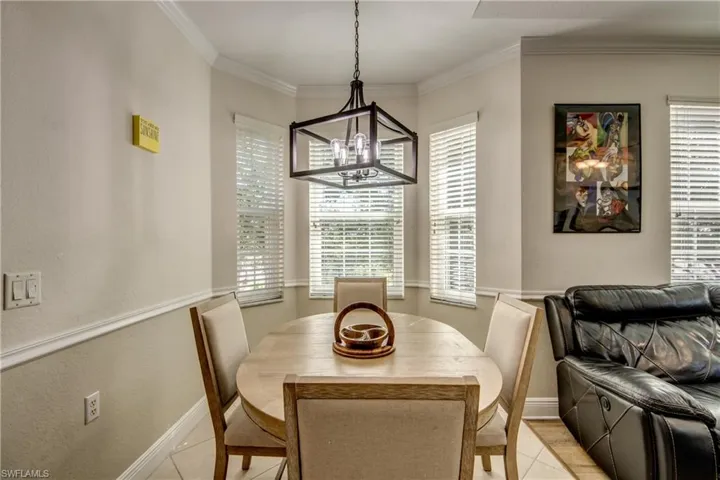 Tiled dining space featuring ornamental molding, a textured wall, and a chandelier