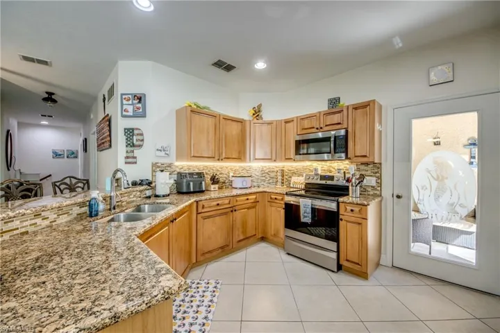 Kitchen with appliances with stainless steel finishes, light stone counters, backsplash, a peninsula, and recessed lighting