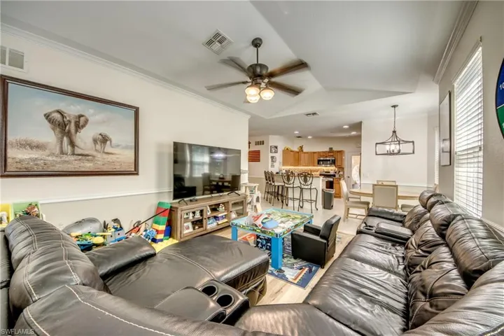Living room with ornamental molding, a ceiling fan, a chandelier, and light wood-type flooring