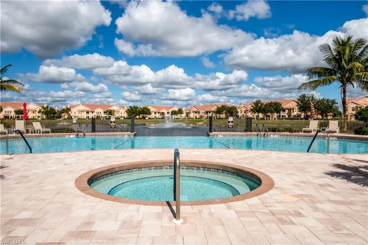 Community pool with a residential view, a patio area, a water view, and a hot tub