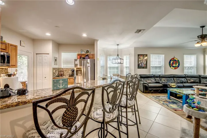 Kitchen featuring a breakfast bar area, light stone countertops, light tile patterned floors, tasteful backsplash, and stainless steel appliances