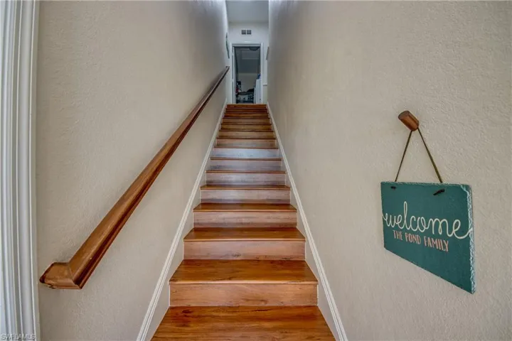 Stairway with a textured wall and wood finished floors