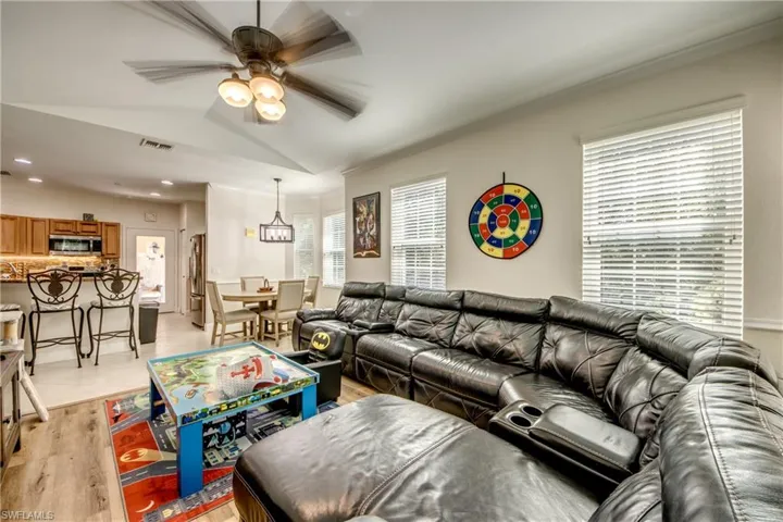 Living area with light wood-type flooring, a ceiling fan, recessed lighting, ornamental molding, and vaulted ceiling