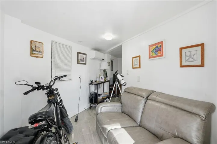 Workout room with wood finish floors and a wall mounted AC - Virtually Edited Image