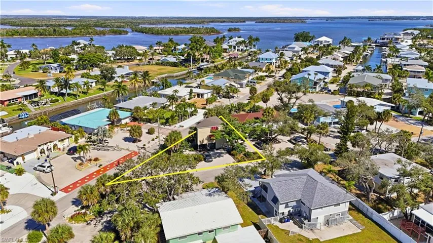 Aerial perspective of suburban area with a nearby body of water and property boundaries highlighted - Virtually Edited Image