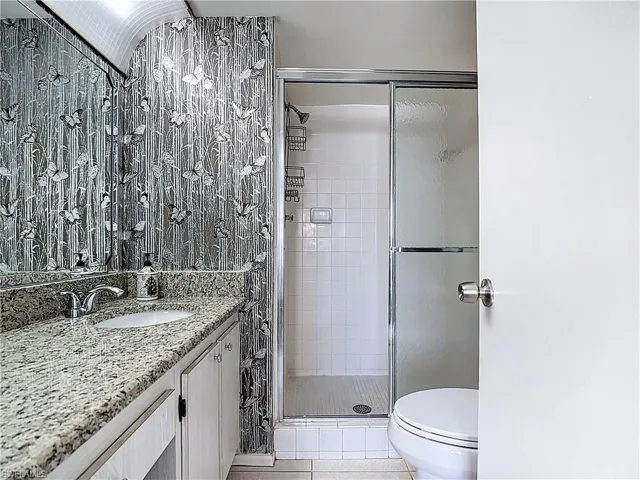 Full bath featuring a shower stall, light tile patterned floors, and vanity