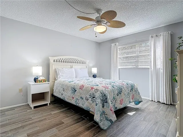 Bedroom featuring wood tiled floors, a textured ceiling, and ceiling fan