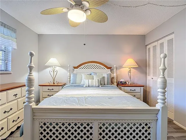 Bedroom with dark wood finished floors, a textured ceiling, a ceiling fan, and a closet
