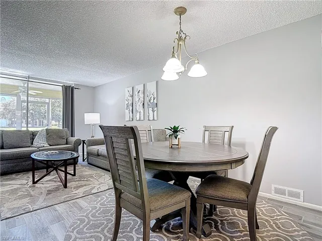 Dining room with a textured ceiling, wood finished floors, and a chandelier