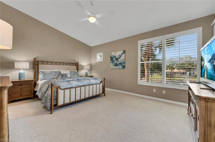 Bedroom with light carpet, vaulted ceiling, and ceiling fan