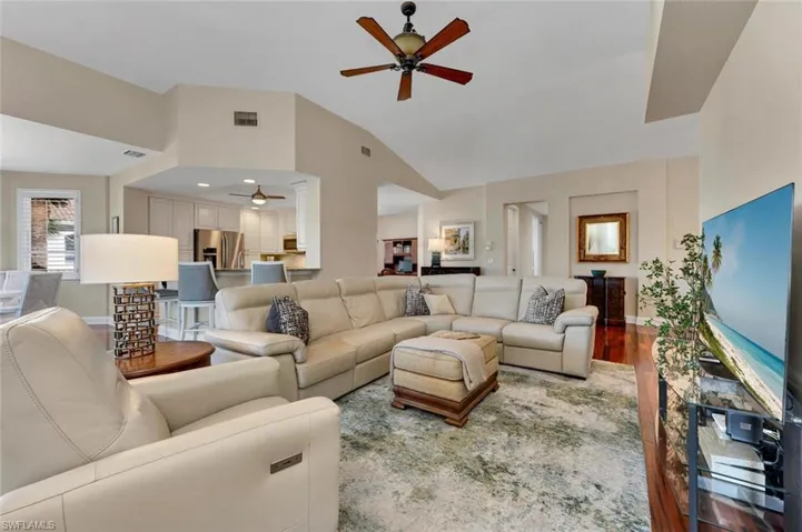Living room with hardwood / wood-style floors, vaulted ceiling, and ceiling fan