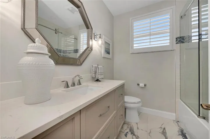 Full bathroom with vanity, toilet, and enclosed tub / shower combo