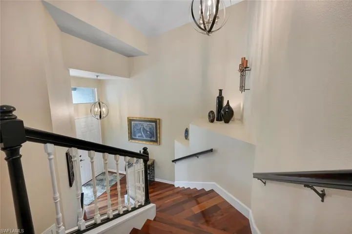 Stairway with a chandelier and wood-type flooring