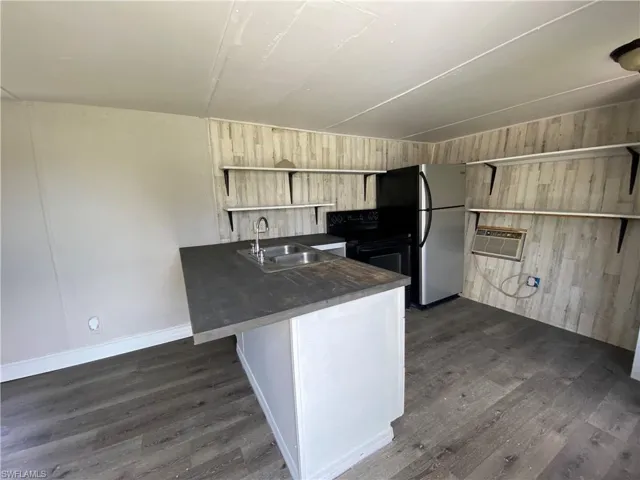 Kitchen with a wall mounted AC, dark wood-type flooring, sink, and kitchen peninsula