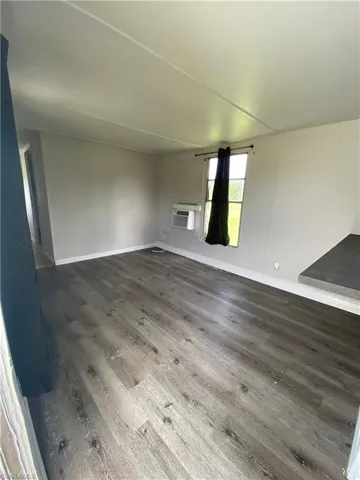 Unfurnished room with dark hardwood / wood-style floors and a wall mounted air conditioner